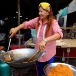 Street food vendor cooking in a wok at a Thai market