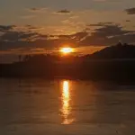 Warm sunrise light over hills and water in Thailand